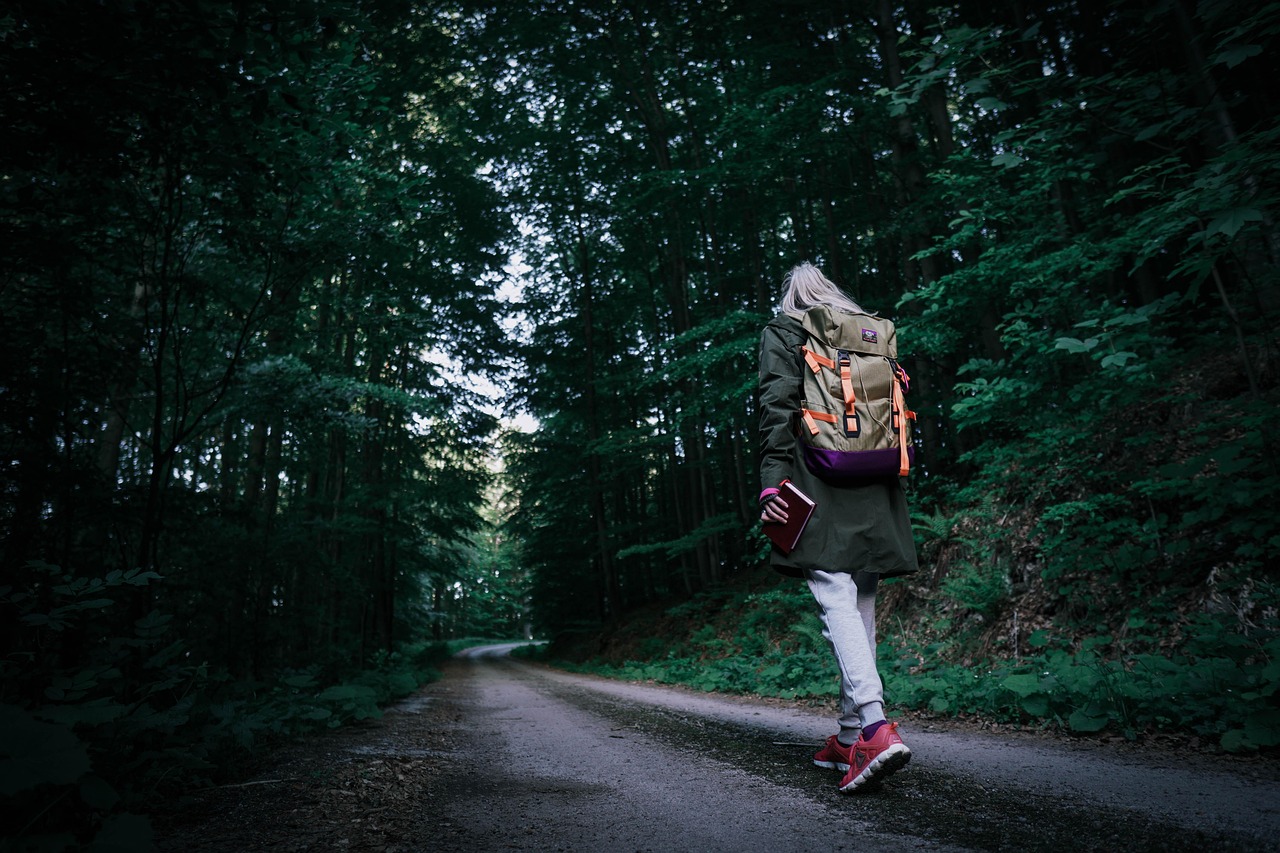 Persona che cammina in un parco, circondata da natura, mentre riflette e si ispira.