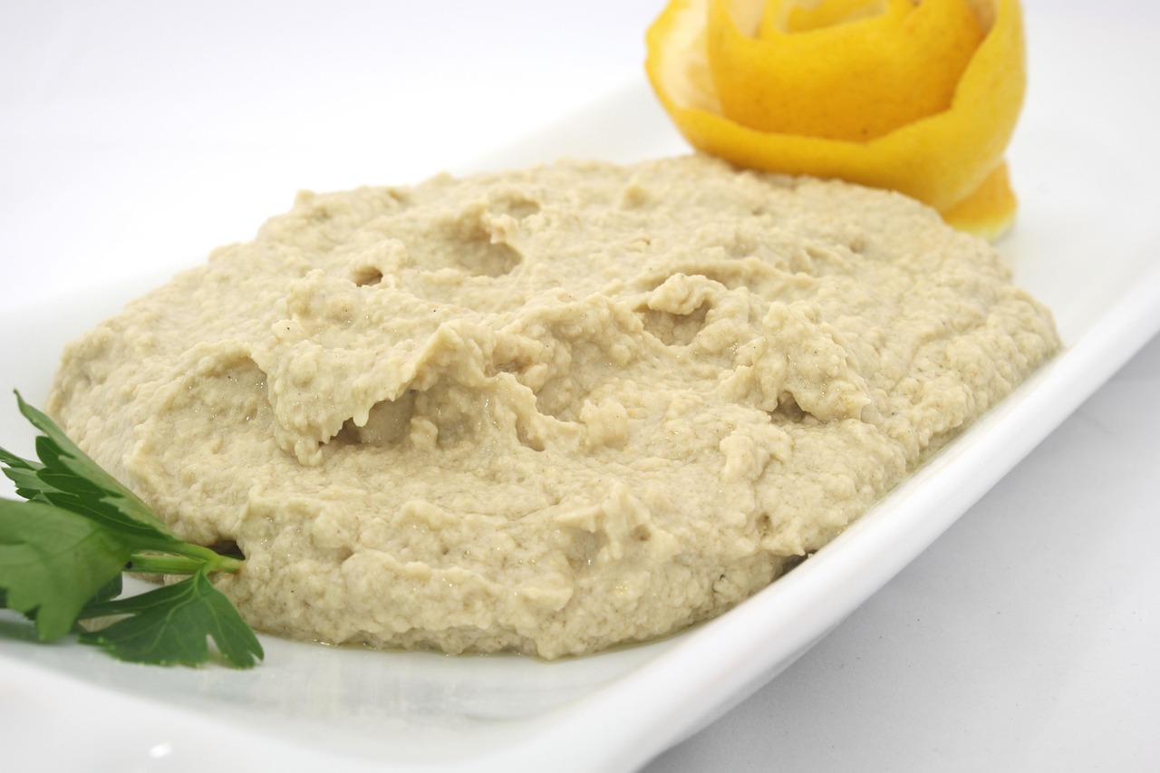 Hummus cremoso con ceci e limone fresco servito in una ciotola decorata con olio d'oliva e paprika.