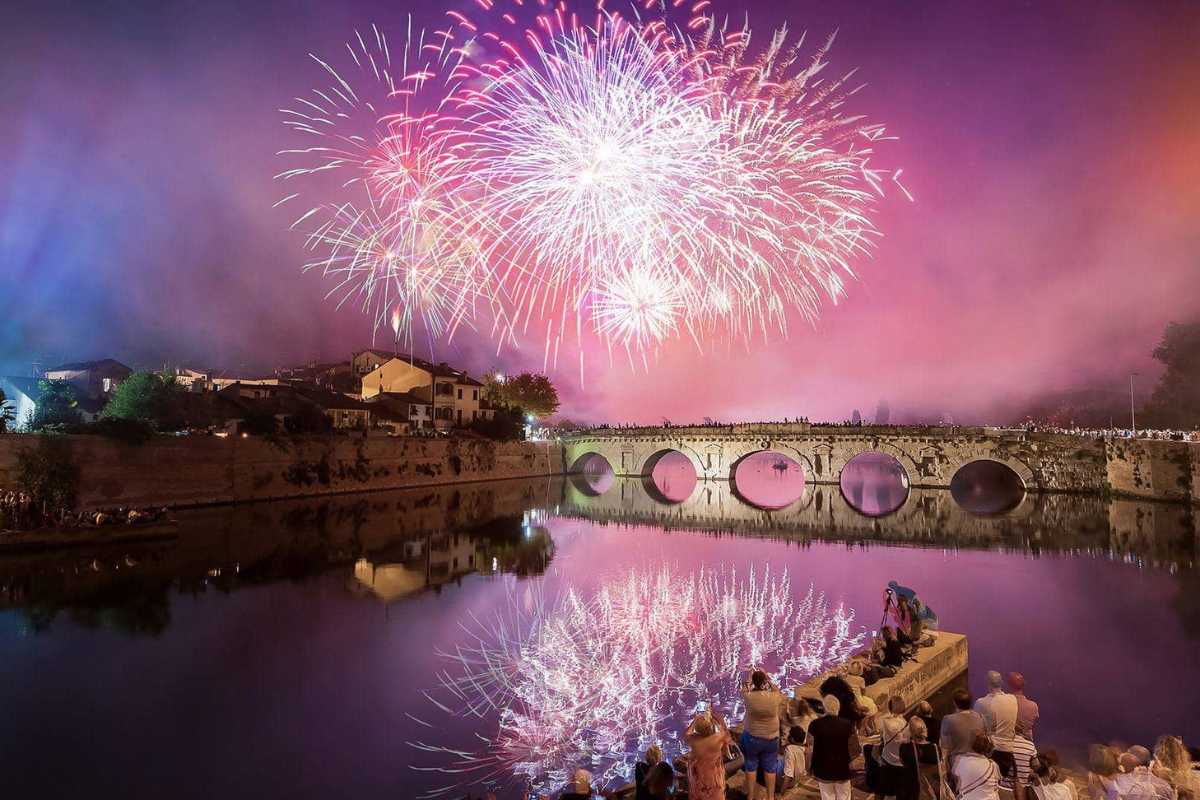 Panorama di una città illuminata per Capodanno, con fuochi d'artificio nel cielo notturno.