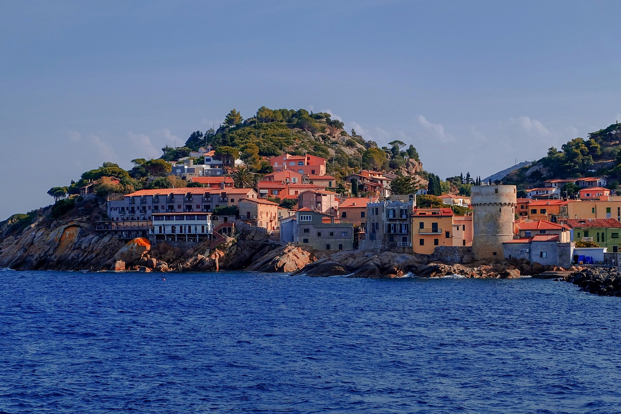 Vista panoramica del borgo dell'Isola del Giglio con spiagge cristalline sullo sfondo.